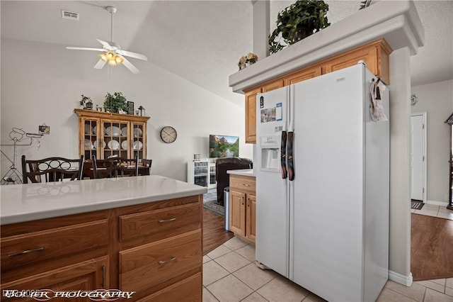 kitchen with lofted ceiling, light tile patterned floors, ceiling fan, and white refrigerator with ice dispenser