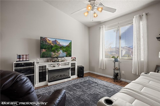 living room with ceiling fan, a textured ceiling, lofted ceiling, and hardwood / wood-style floors