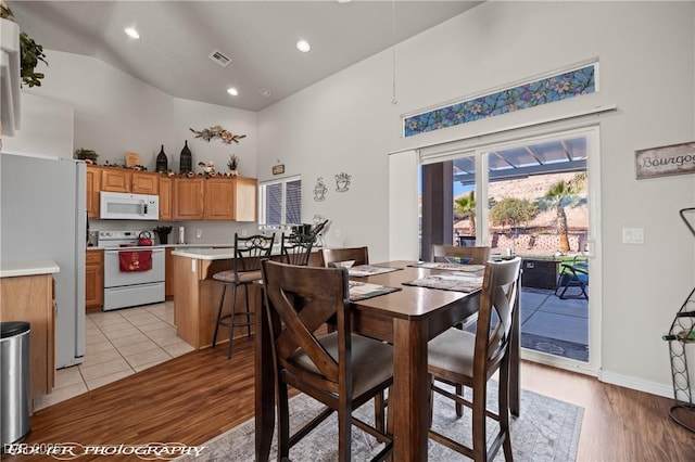 dining area with high vaulted ceiling and light wood-type flooring