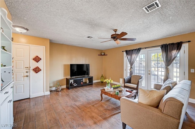 living room featuring hardwood / wood-style flooring, a textured ceiling, ceiling fan, and french doors