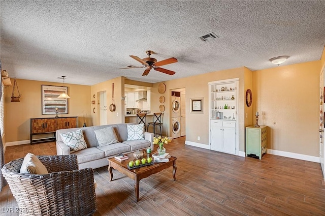 living room with hardwood / wood-style flooring, a textured ceiling, stacked washer / drying machine, and ceiling fan