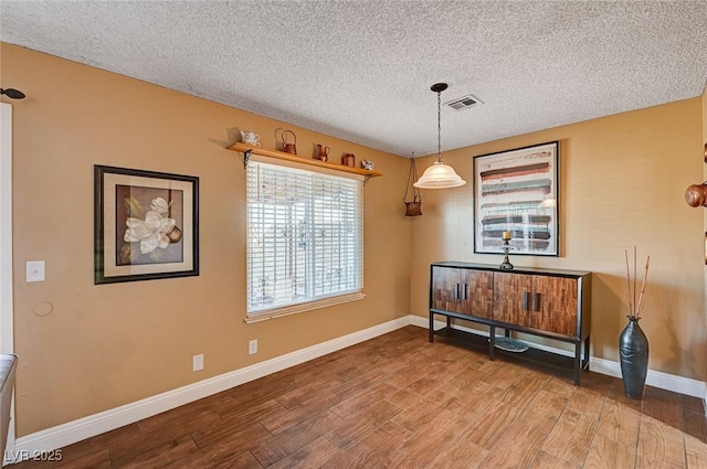 dining space featuring a textured ceiling and hardwood / wood-style floors