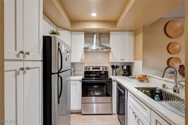 kitchen with white cabinets, appliances with stainless steel finishes, wall chimney range hood, decorative backsplash, and sink