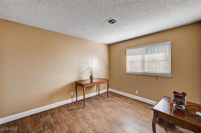 office space featuring light wood-type flooring and a textured ceiling