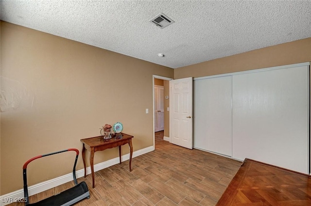 bedroom featuring light hardwood / wood-style floors, a textured ceiling, and a closet