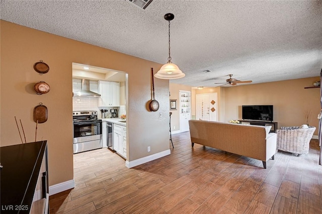 kitchen featuring light hardwood / wood-style floors, white cabinetry, wall chimney range hood, pendant lighting, and stainless steel appliances