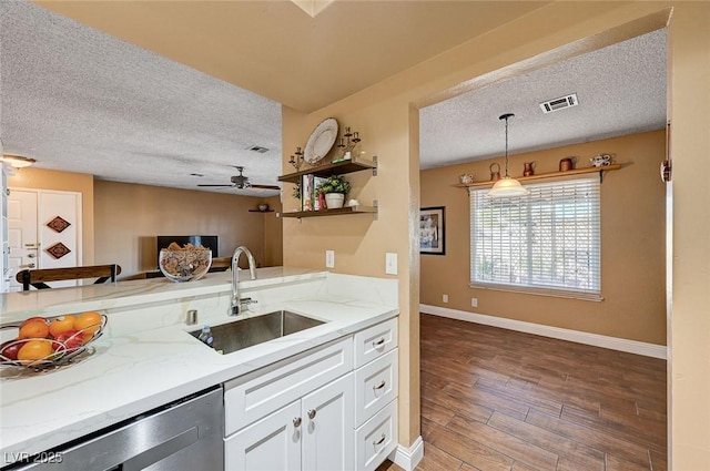 kitchen with sink, stainless steel dishwasher, light stone countertops, and hanging light fixtures