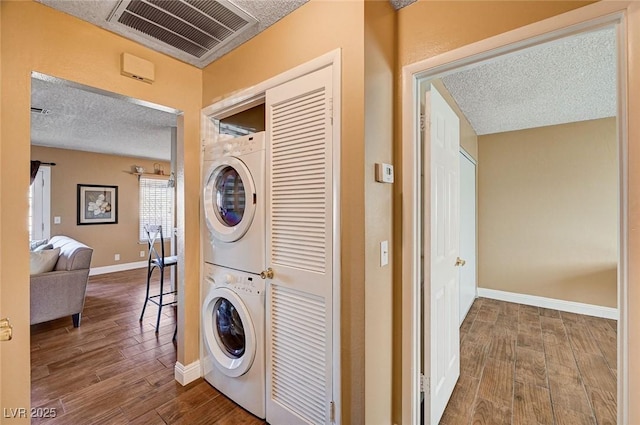 laundry room featuring stacked washer / drying machine, hardwood / wood-style floors, and a textured ceiling