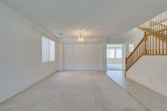 tiled empty room featuring a chandelier