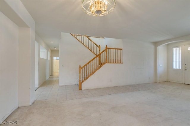 unfurnished living room featuring light colored carpet, a wealth of natural light, and an inviting chandelier