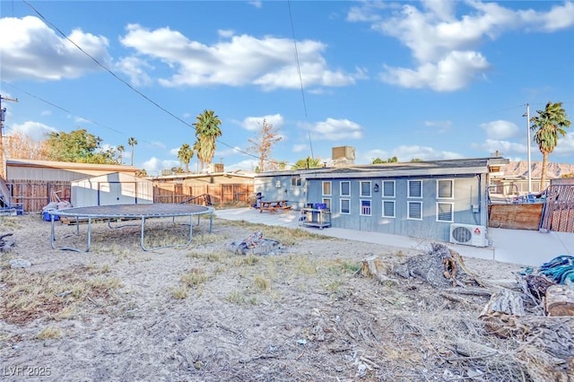 rear view of property with a trampoline, a storage unit, and ac unit