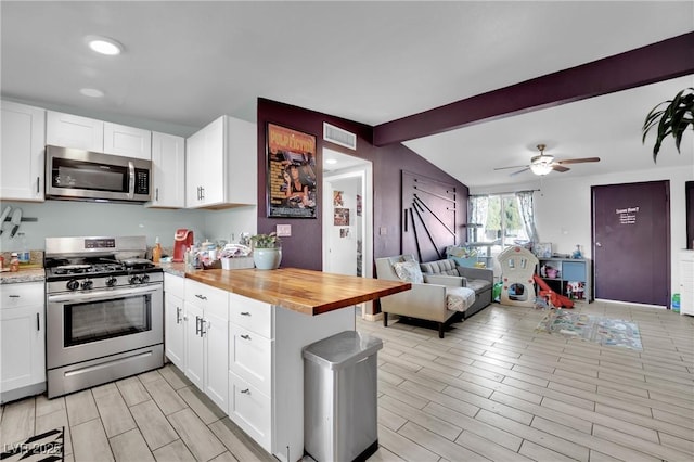 kitchen with white cabinets, appliances with stainless steel finishes, butcher block countertops, and vaulted ceiling with beams