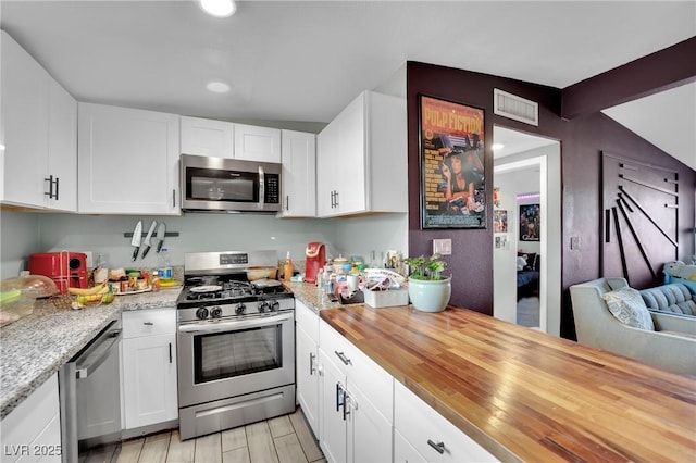 kitchen featuring appliances with stainless steel finishes, wood counters, white cabinetry, and light hardwood / wood-style flooring