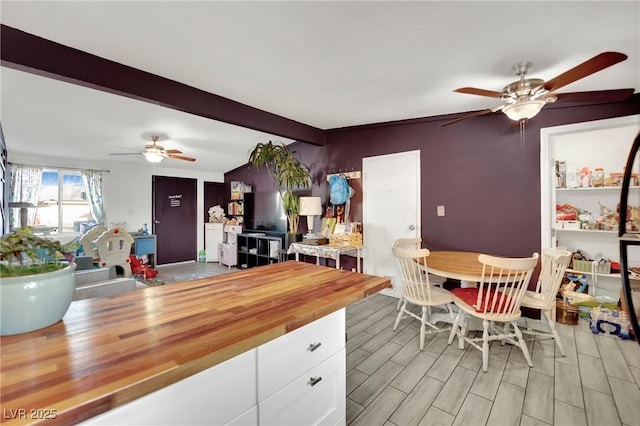 kitchen featuring ceiling fan, vaulted ceiling with beams, white cabinets, and wood counters