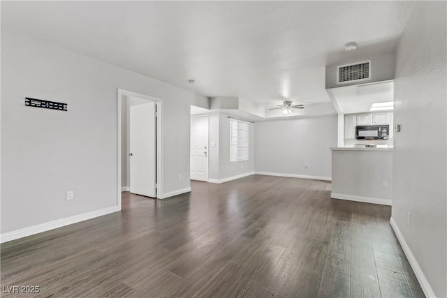 unfurnished living room featuring ceiling fan and dark wood-type flooring