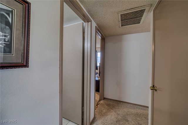 hallway with a textured ceiling and light colored carpet