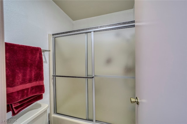 bathroom featuring toilet and combined bath / shower with glass door