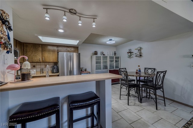 kitchen with appliances with stainless steel finishes, a skylight, backsplash, kitchen peninsula, and a breakfast bar area