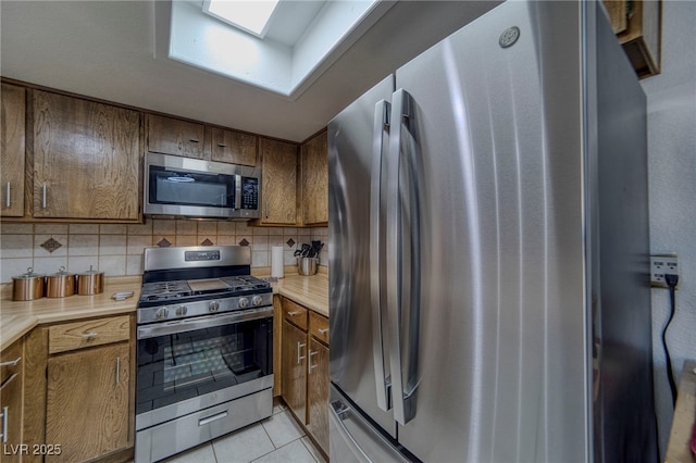 kitchen with tasteful backsplash, light tile patterned floors, a skylight, and appliances with stainless steel finishes