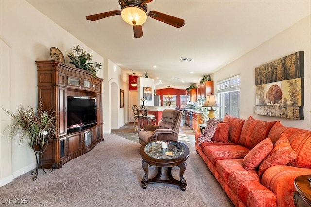 carpeted living room with ceiling fan