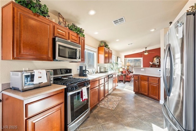 kitchen featuring kitchen peninsula, vaulted ceiling, ceiling fan, and stainless steel appliances