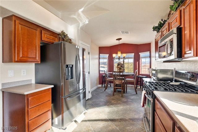 kitchen featuring stainless steel appliances, a chandelier, vaulted ceiling, and decorative light fixtures