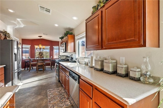 kitchen featuring vaulted ceiling, hanging light fixtures, appliances with stainless steel finishes, sink, and a notable chandelier