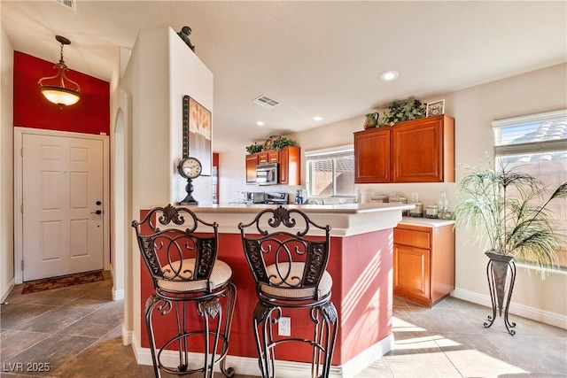 kitchen featuring decorative light fixtures, a wealth of natural light, kitchen peninsula, and a kitchen breakfast bar