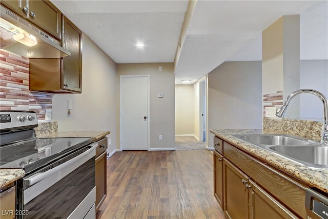 kitchen with light stone countertops, appliances with stainless steel finishes, dark hardwood / wood-style flooring, sink, and backsplash