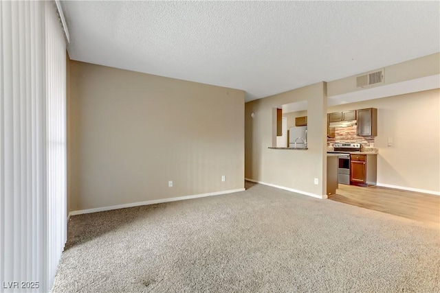 unfurnished living room with light carpet and a textured ceiling