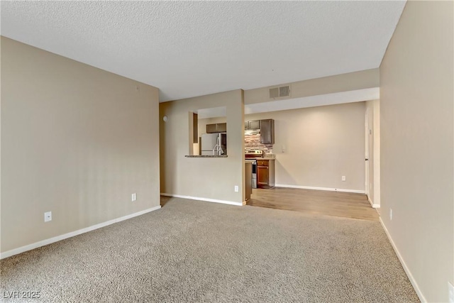 unfurnished living room with a textured ceiling and light carpet