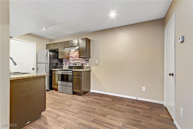 kitchen featuring stainless steel appliances, backsplash, light wood-type flooring, light stone countertops, and sink