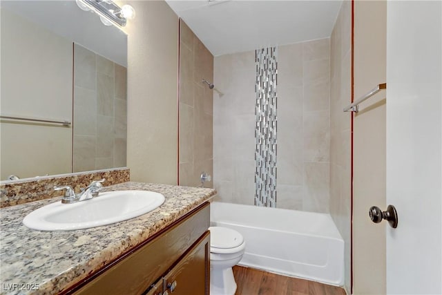 full bathroom with toilet, tiled shower / bath combo, hardwood / wood-style floors, and vanity