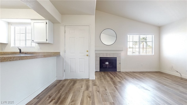 interior space with light wood-type flooring, lofted ceiling, a fireplace, and plenty of natural light