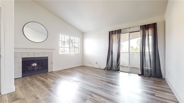 unfurnished living room with vaulted ceiling, a fireplace, and light hardwood / wood-style floors