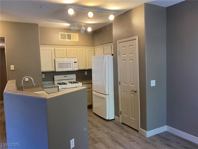 kitchen featuring kitchen peninsula, sink, white appliances, white cabinetry, and light hardwood / wood-style flooring