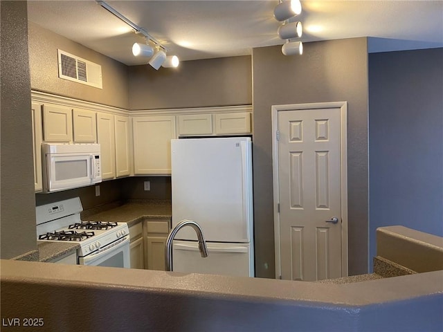 kitchen featuring rail lighting, white cabinets, and white appliances