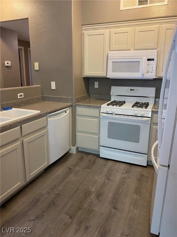 kitchen with dark hardwood / wood-style flooring, sink, white cabinets, and white appliances