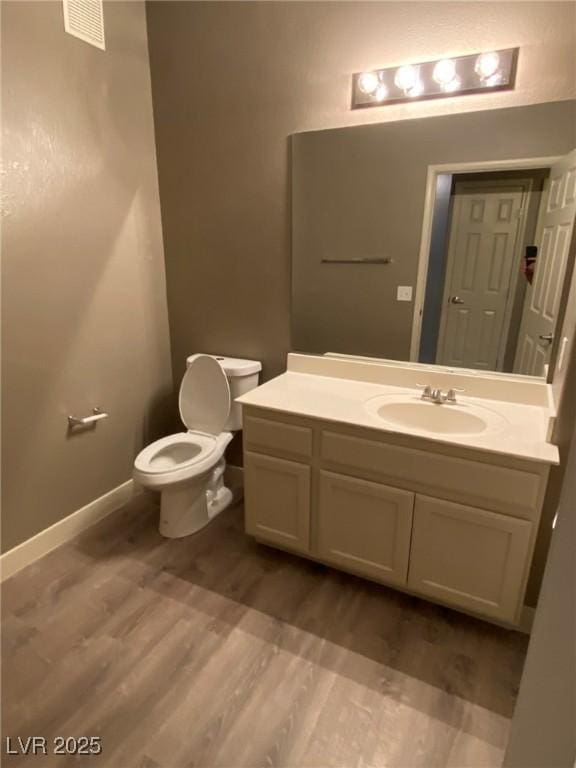 bathroom with hardwood / wood-style floors, toilet, and vanity