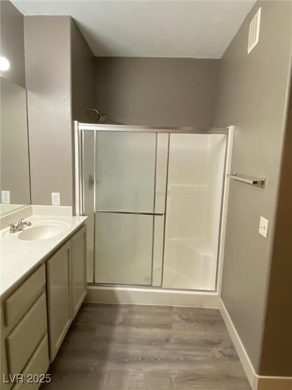 bathroom with a shower with shower door, vanity, and wood-type flooring