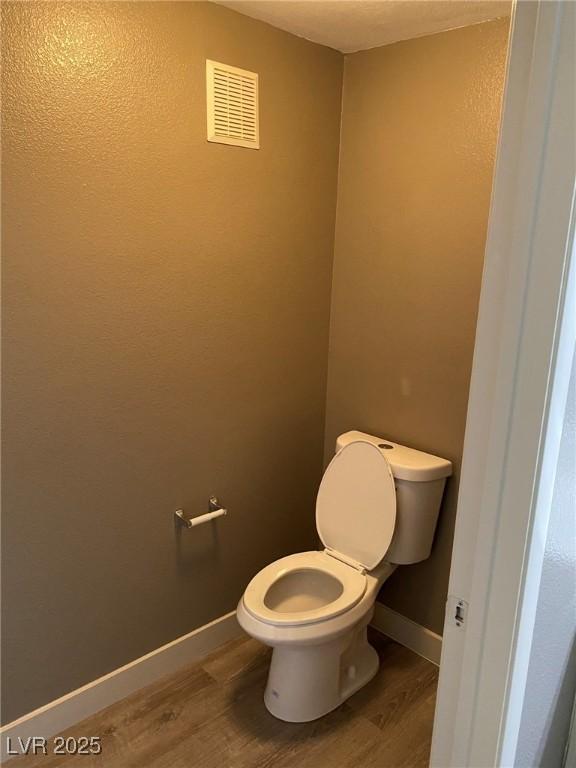 bathroom featuring toilet and wood-type flooring