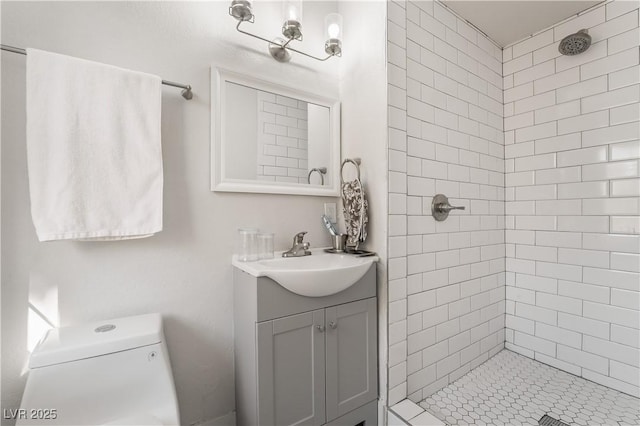 bathroom featuring toilet, tiled shower, and vanity