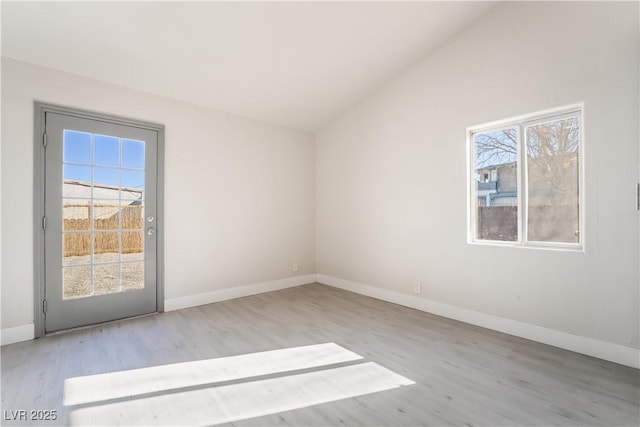 spare room with light hardwood / wood-style floors, lofted ceiling, and a healthy amount of sunlight