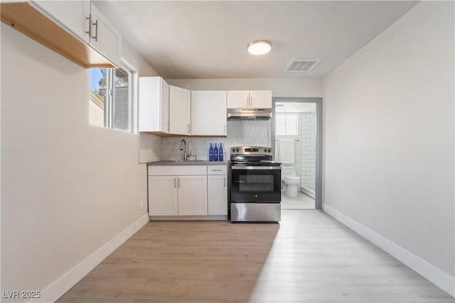 kitchen featuring stainless steel electric stove, sink, white cabinetry, and tasteful backsplash