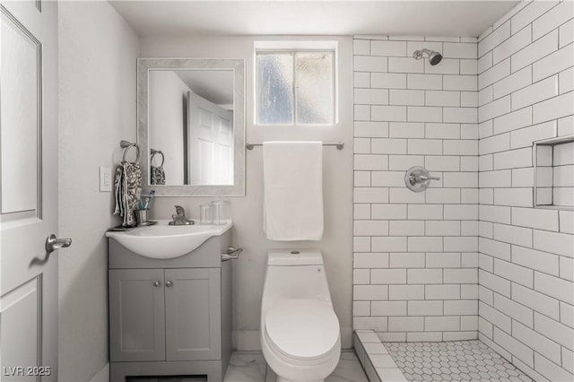 bathroom with toilet, vanity, and tiled shower