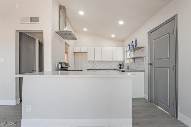 kitchen featuring decorative backsplash, white cabinets, a center island, and extractor fan