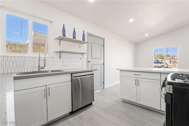 kitchen with tasteful backsplash, vaulted ceiling, sink, appliances with stainless steel finishes, and white cabinets