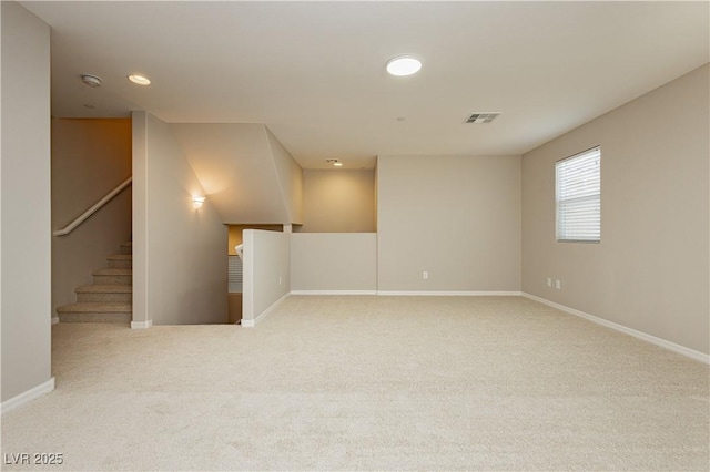 carpeted empty room featuring visible vents, baseboards, and stairs