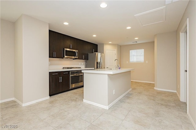 kitchen with an island with sink, appliances with stainless steel finishes, light countertops, and a sink