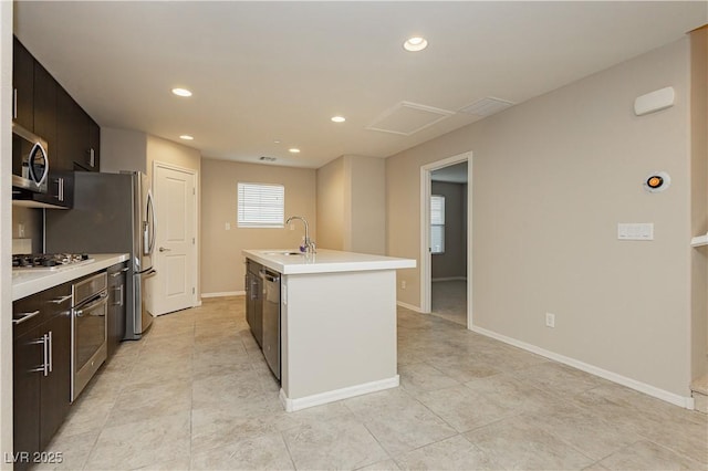 kitchen featuring a center island with sink, stainless steel appliances, light countertops, a sink, and recessed lighting